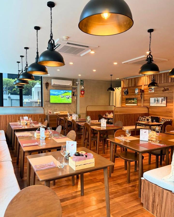 The dining room at Swiss Peak, wooden tables under black pendant lamps